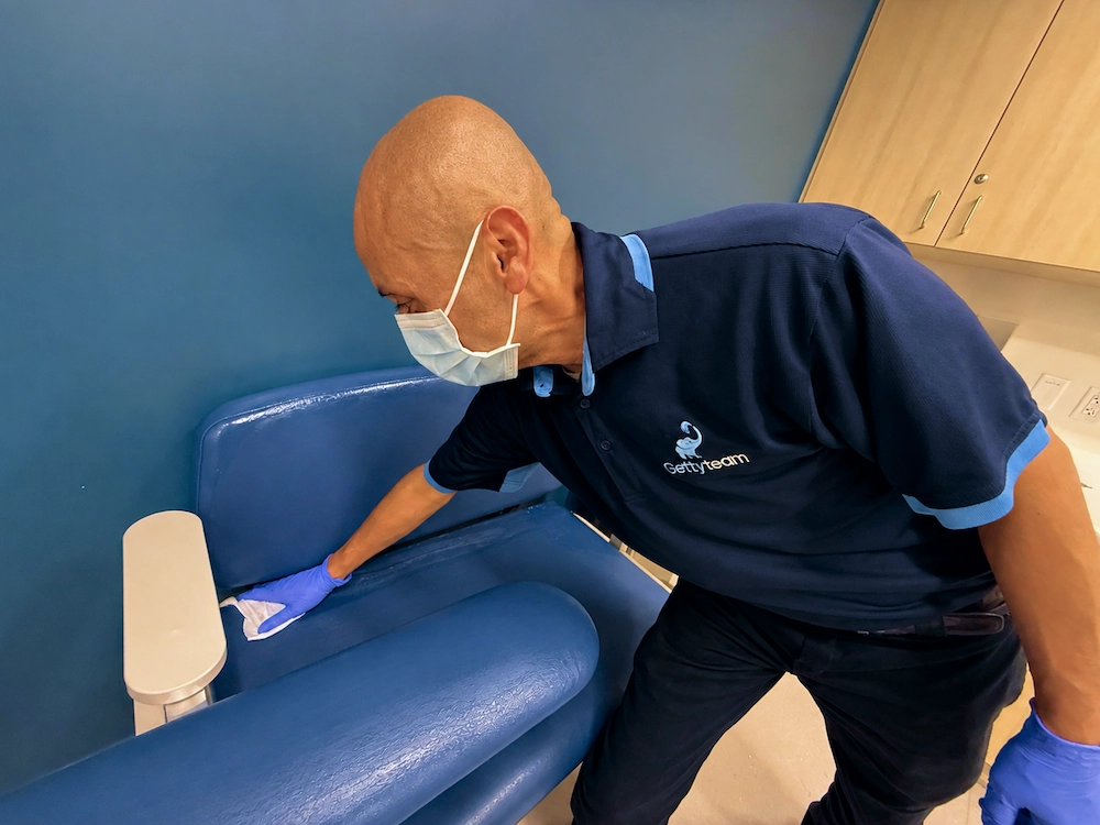 Getty Team environmental services technician disinfecting an examination chair in a healthcare facility