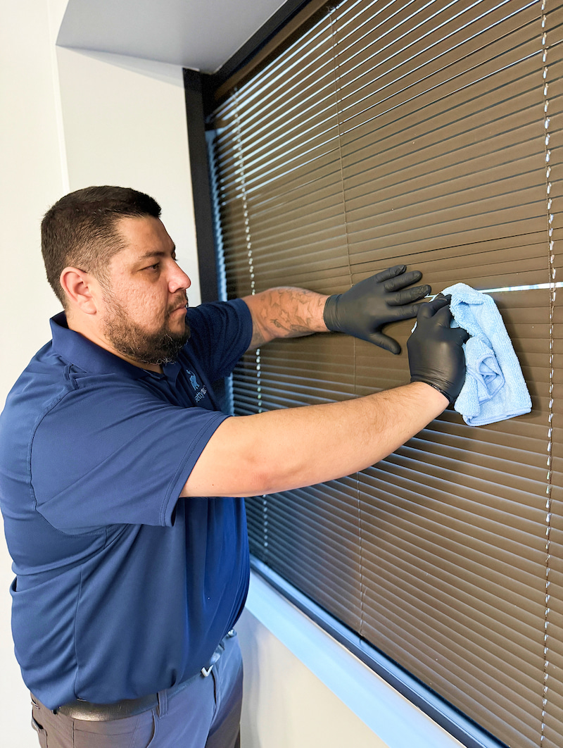Getty Team janitorial employee cleaning office window blinds